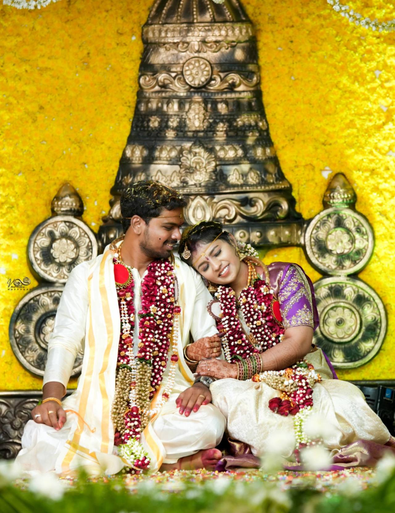 Bride and groom during a traditional Indian wedding ceremony with elegant decorations and family blessings.